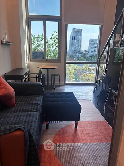Modern living room with city view, featuring stylish furniture and large windows for natural light.