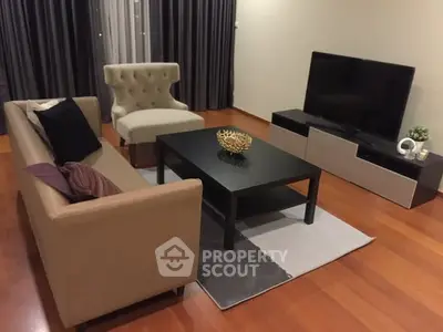 Modern living room with stylish furniture and flat-screen TV on wooden flooring.