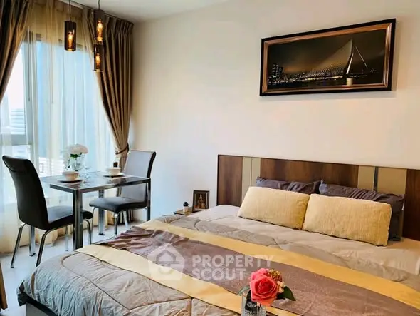 Elegant bedroom with cozy dining area and large window view.