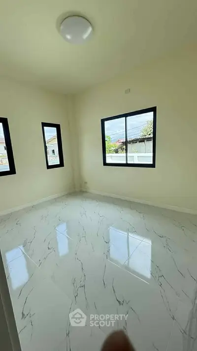 Bright and airy room with large windows and marble flooring, perfect for a modern living space.
