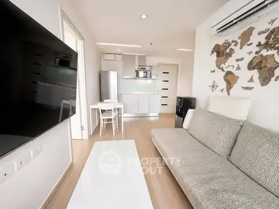 Modern living room with sleek kitchen, wall-mounted TV, and stylish decor in open-concept apartment.