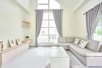 Spacious modern living room with high ceilings and large windows, featuring elegant decor and a cozy seating area.