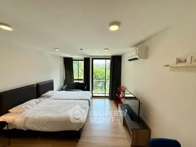 Spacious modern bedroom with twin beds and balcony view in a stylish apartment.