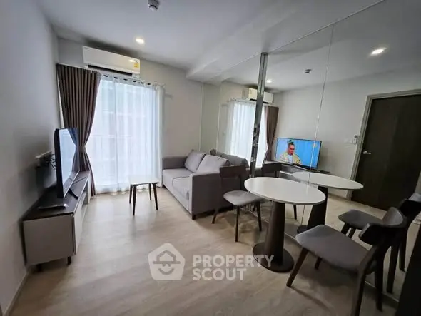 Modern living room with mirrored wall, cozy sofa, and flat-screen TV in a stylish apartment.