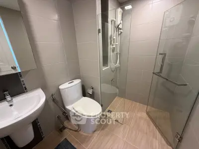 Modern bathroom with glass shower and sleek fixtures in contemporary apartment.