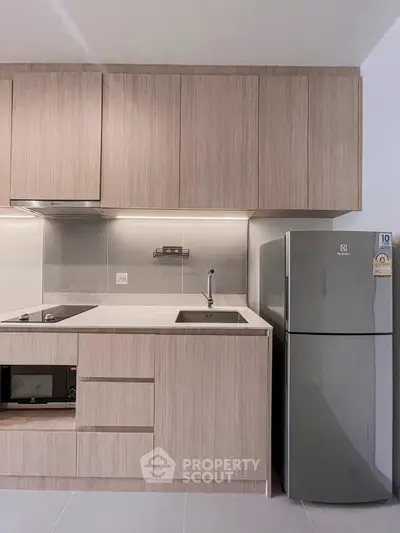 Modern kitchen with sleek cabinetry and stainless steel fridge in a stylish apartment.