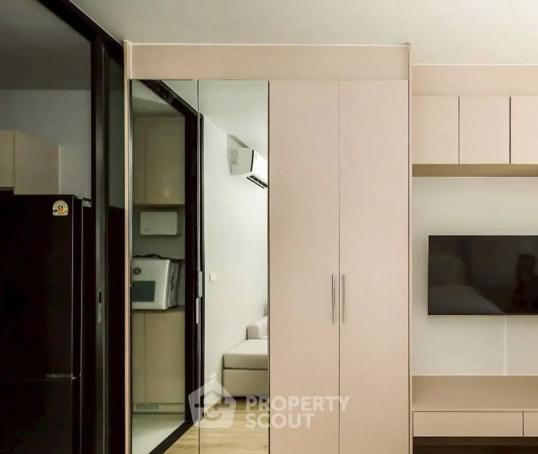 Modern living room with sleek cabinetry and wall-mounted TV in a stylish apartment.