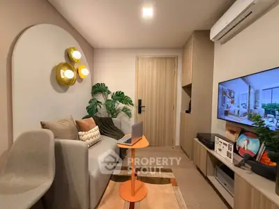Modern living room with stylish decor and cozy seating area, featuring a wall-mounted TV and air conditioning.