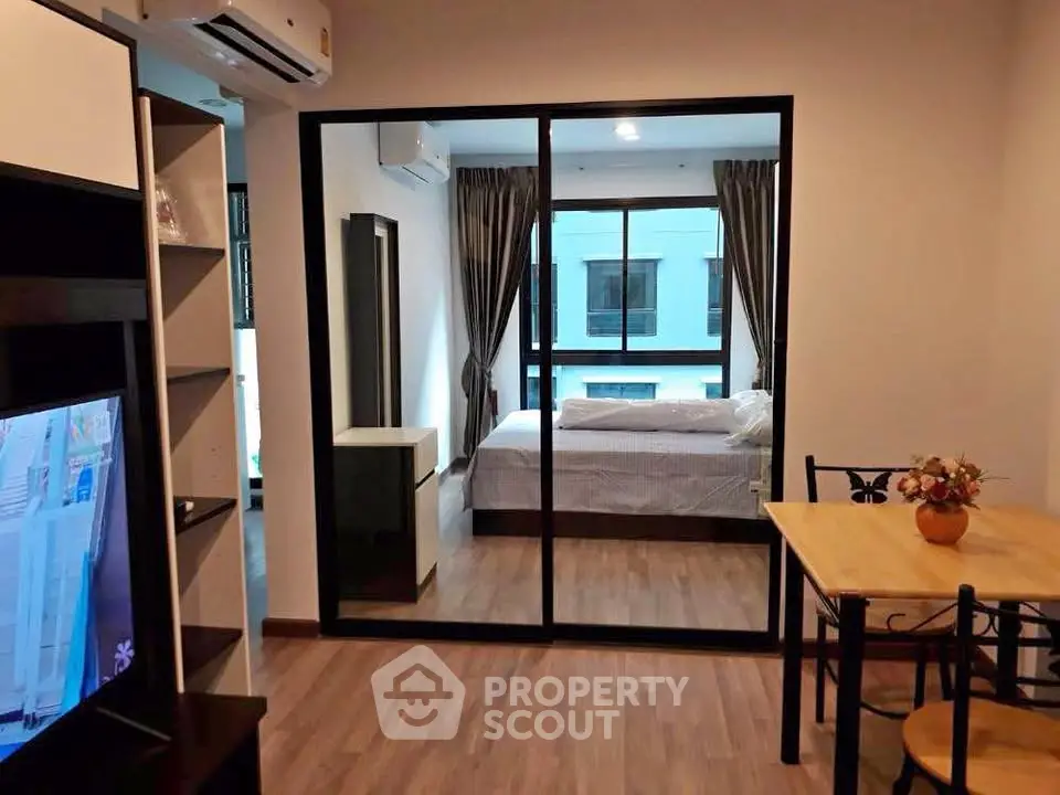 Modern apartment interior with open living and dining area, featuring a view into a cozy bedroom.
