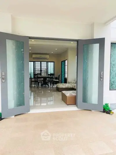 Spacious living room with elegant glass doors and modern decor, perfect for family gatherings.