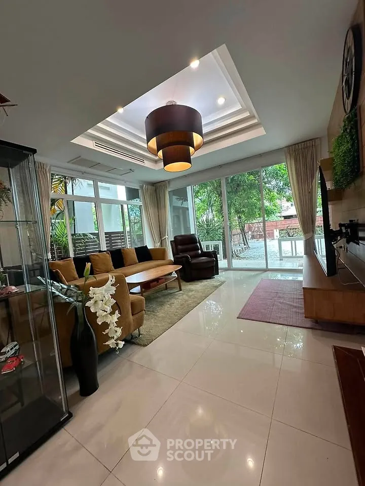 Spacious living room with modern decor and large windows offering garden views.