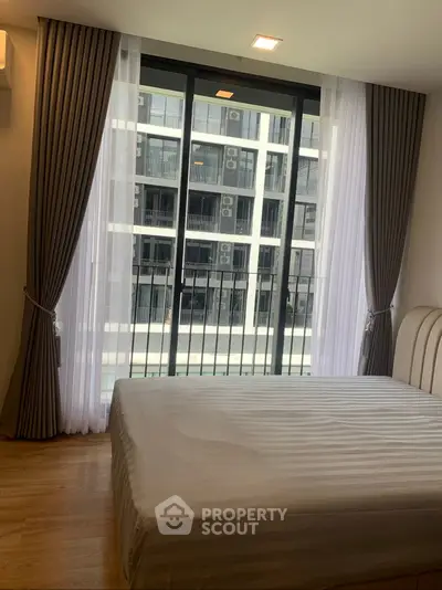 Modern bedroom with large window offering city view in high-rise apartment