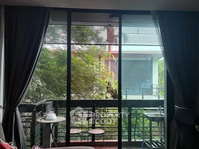 Charming balcony view with lush greenery and cozy seating area, perfect for relaxation.