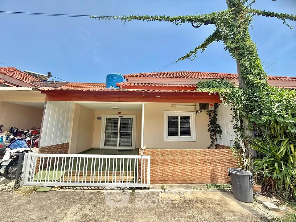 Charming single-story home with red roof and lush greenery, perfect for cozy living.