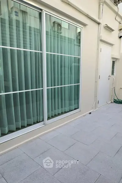 Spacious balcony with sliding glass doors and tiled flooring, perfect for outdoor relaxation.