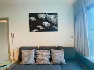 Modern living room with stylish sofa and jellyfish artwork, featuring natural light and elegant decor.