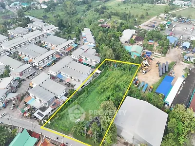 Aerial view of residential area with adjacent green land for development.