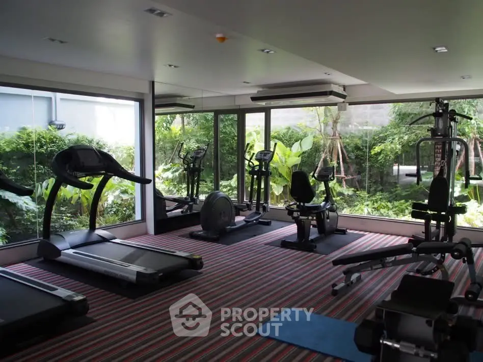Modern gym with lush garden view and state-of-the-art fitness equipment in luxury real estate property.