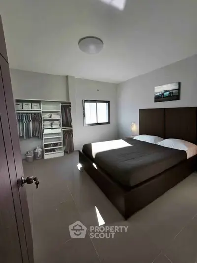 Spacious bedroom with modern decor and ample natural light, featuring a stylish wardrobe.