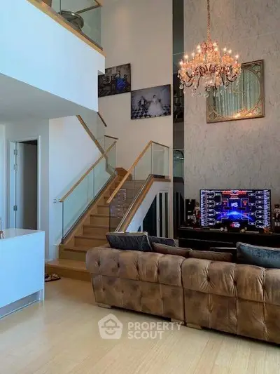Luxurious living room with high ceiling, elegant chandelier, and stylish staircase in modern home.