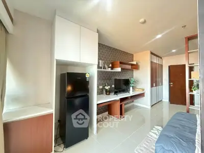 Modern living room with sleek design, featuring a black fridge, TV, and stylish shelving.