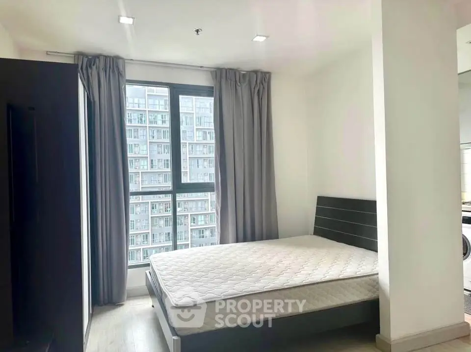 Modern bedroom with large window and city view in high-rise apartment