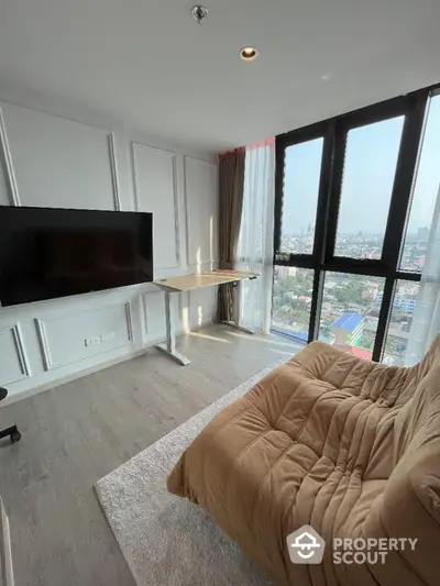 Modern living room with large window and city view, featuring a cozy sofa and flat-screen TV.