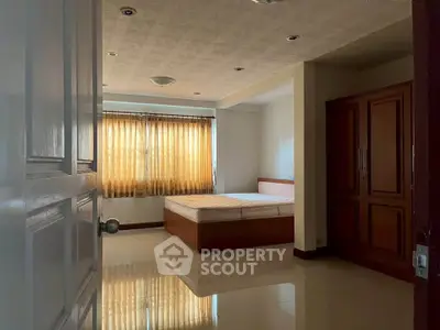 Spacious bedroom with large window and elegant wooden wardrobe
