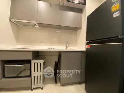 Modern kitchen with sleek cabinets, black fridge, and built-in microwave in a compact layout.