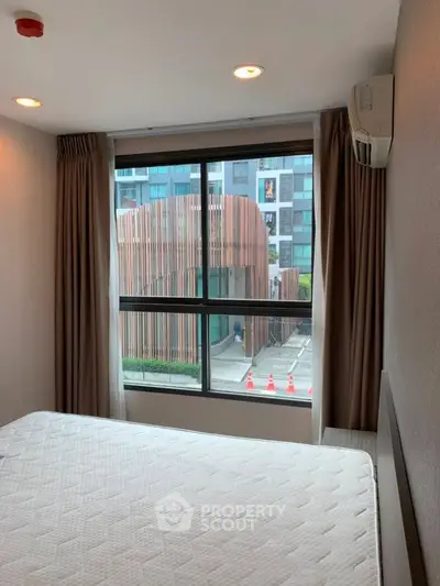 Modern bedroom with large window offering urban view and natural light.
