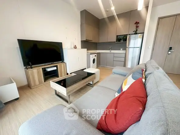 Modern living room with stylish furniture and open kitchen layout featuring appliances.