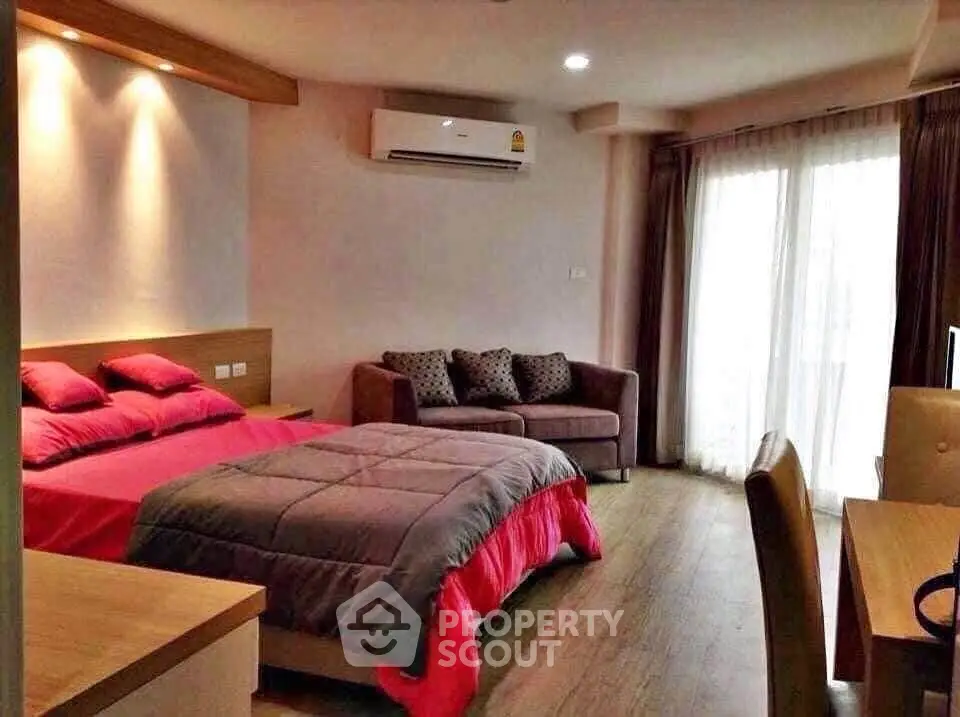 Spacious bedroom with modern decor and natural light from large windows.