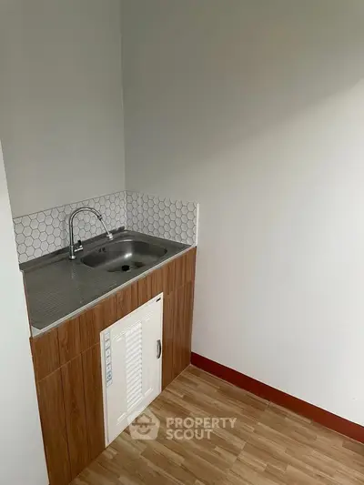 Compact kitchen area with modern sink and wooden cabinetry