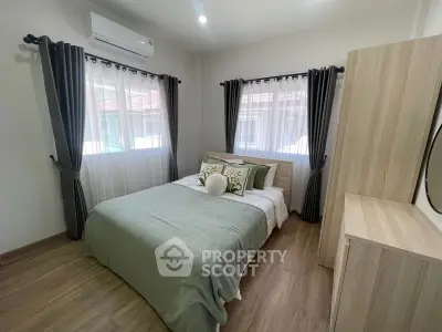 Cozy bedroom with modern decor, wooden flooring, and ample natural light from large windows.