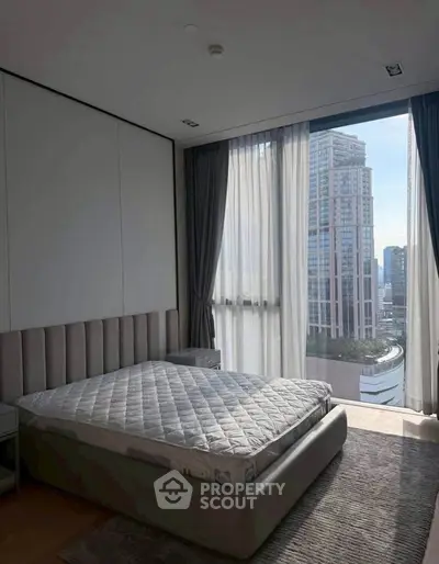 Modern bedroom with large windows offering stunning city views in a high-rise apartment.