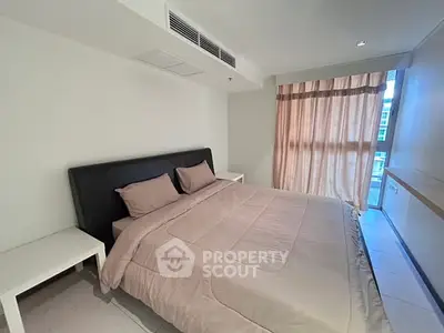 Spacious bedroom with modern decor and large window offering natural light.