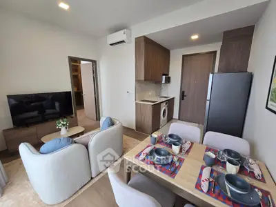 Modern open-plan living room with kitchen and dining area, featuring stylish furniture and appliances.