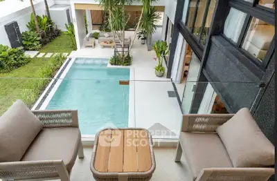 Luxurious modern home with pool view from balcony, featuring stylish outdoor seating and lush greenery.