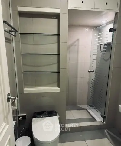 Modern bathroom with sleek shower and toilet, featuring minimalist design and neutral tones.