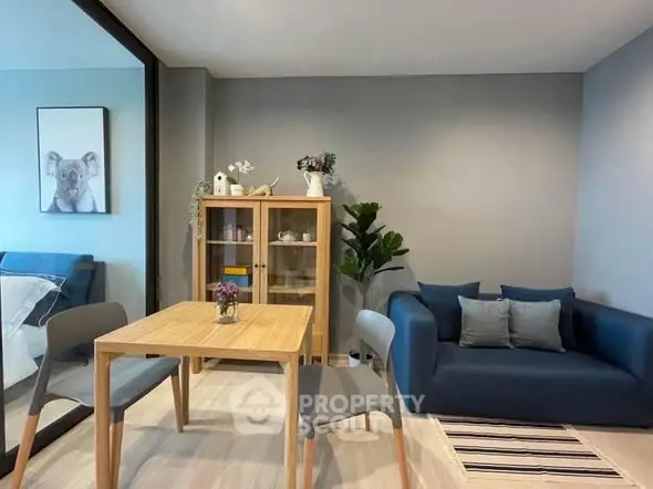 Modern living room with stylish furniture and decor, featuring a cozy blue sofa and wooden dining set.