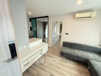 Modern living room with sleek design and air conditioning, featuring a cozy gray sofa and stylish flooring.