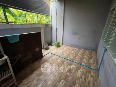 Spacious utility area with tiled flooring and natural light, ideal for laundry or storage.