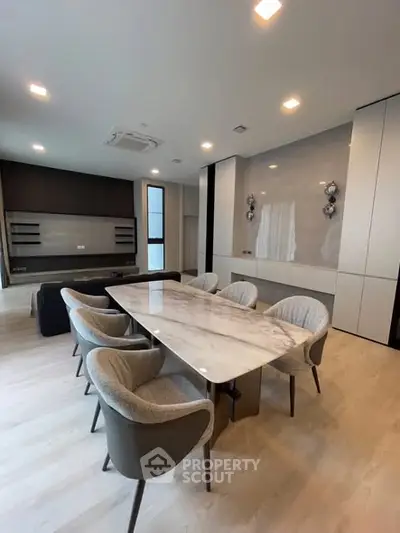 Elegant dining area with modern marble table and plush chairs in a stylish open-plan living space.