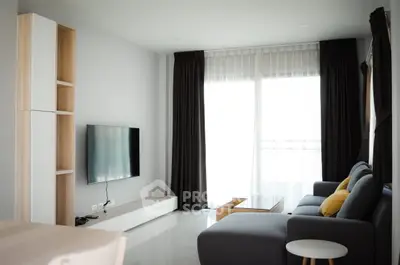 Modern living room with sleek furniture and large window, offering a bright and inviting atmosphere.