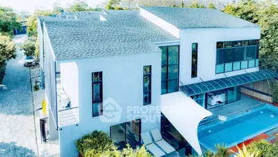 Modern luxury home with sleek design and private pool, surrounded by lush greenery.