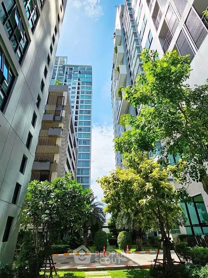 Modern high-rise buildings with lush greenery and clear blue sky view.