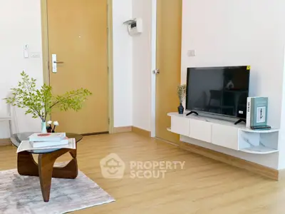 Modern living room with stylish furniture and mounted TV, showcasing elegant wooden flooring.