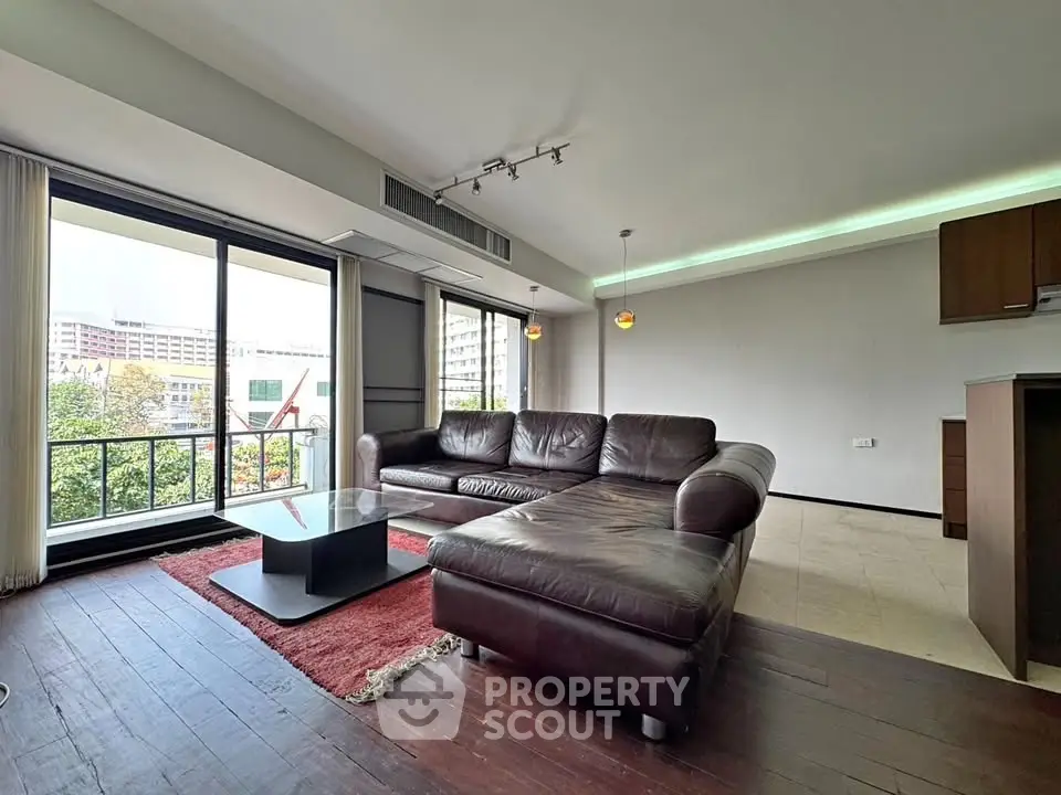 Spacious living room with leather sectional and city view balcony.