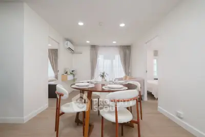 Modern dining area with elegant table and chairs in a bright, open-plan apartment interior.