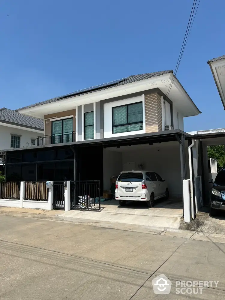 Modern two-story house with carport in a suburban neighborhood, featuring sleek design and ample parking space.